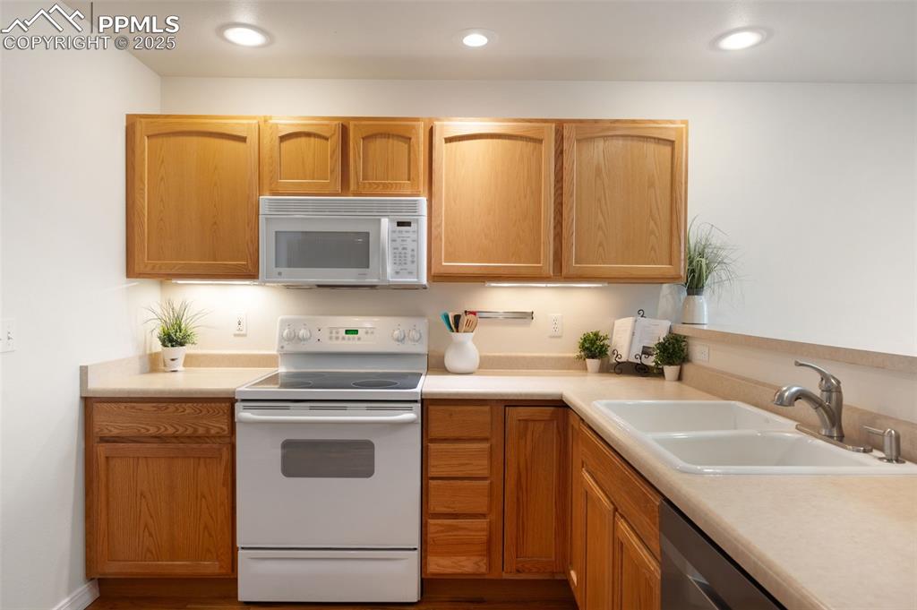 Image 12 of 38: Kitchen featuring white appliances, light countertops, dark wood-type floor