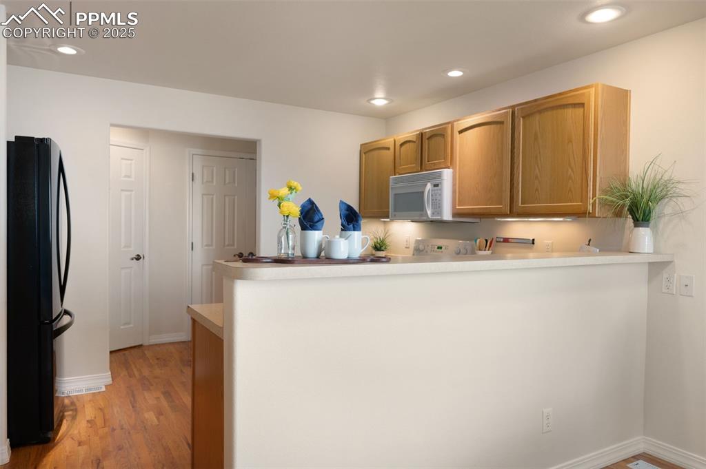 Image 13 of 38: Kitchen with freestanding refrigerator, light wood-type flooring, recessed