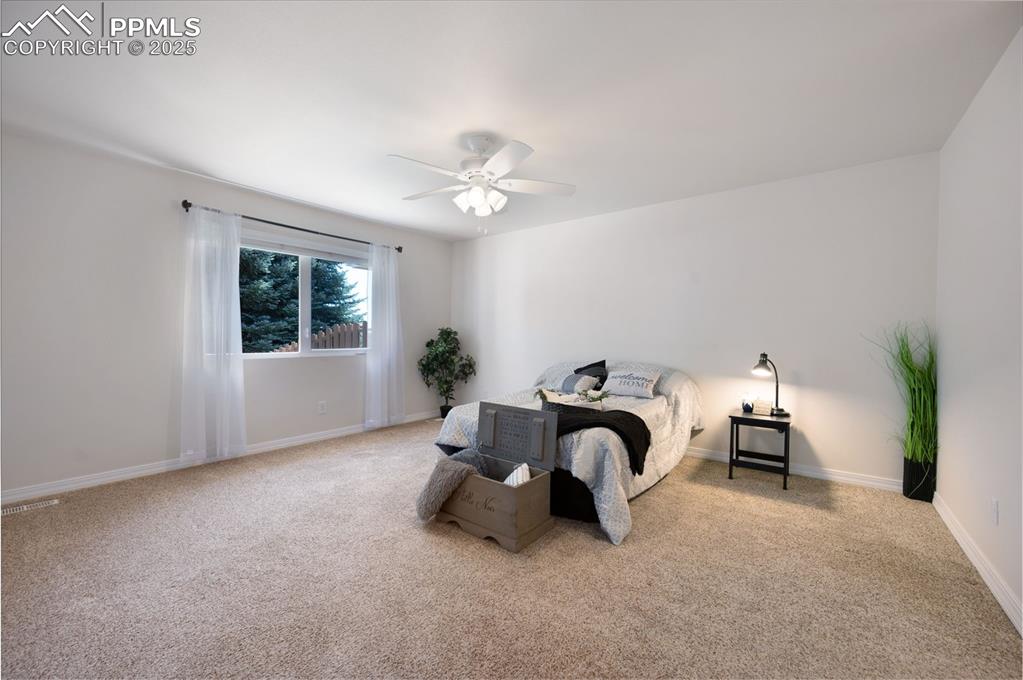 Image 17 of 38: Carpeted bedroom with a ceiling fan and baseboards
