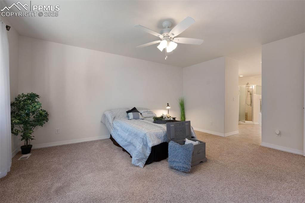 Image 19 of 38: Bedroom with light carpet, ceiling fan, and connected bathroom