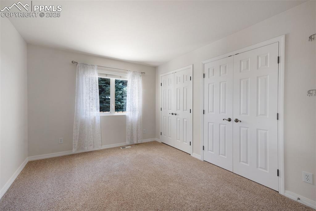 Image 25 of 38: Unfurnished bedroom featuring two closets and light colored carpet