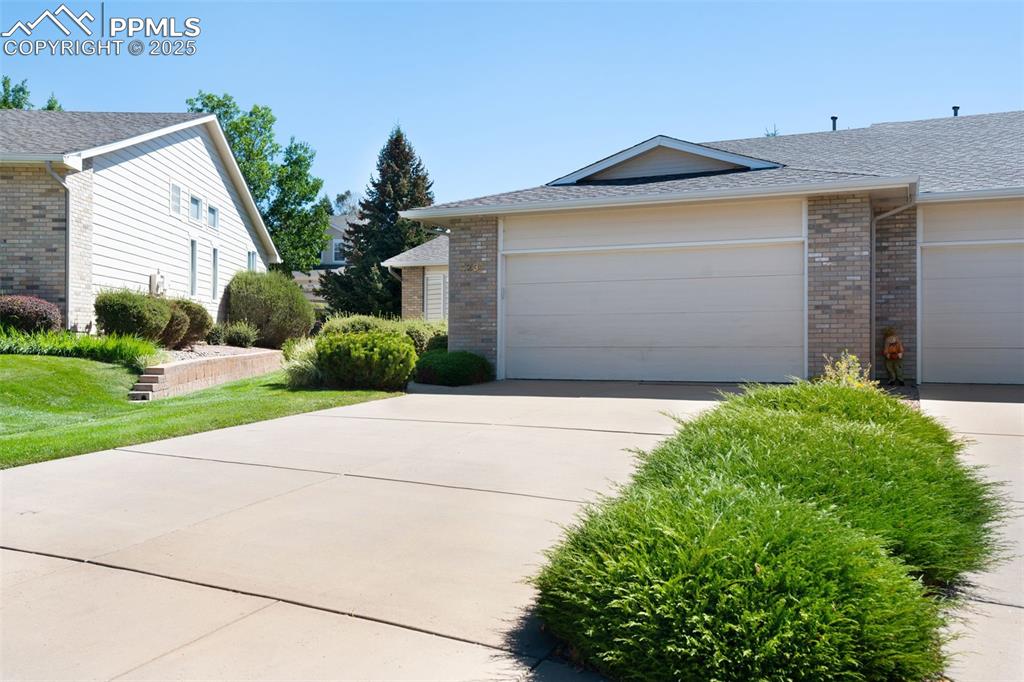 Image 34 of 38: View of property exterior featuring brick siding, a shingled roof, and conc