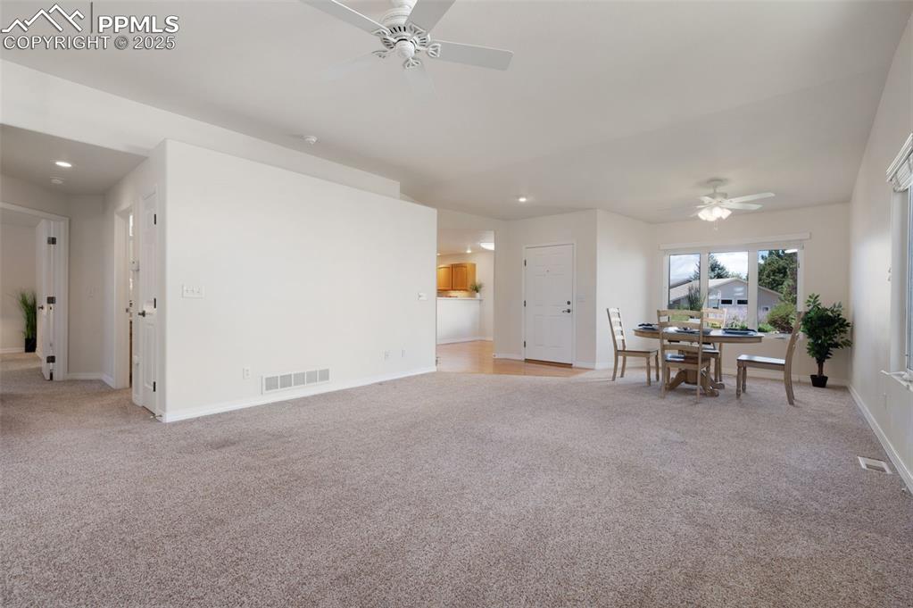 Image 6 of 38: Living area featuring a ceiling fan, light colored carpet, and recessed lig