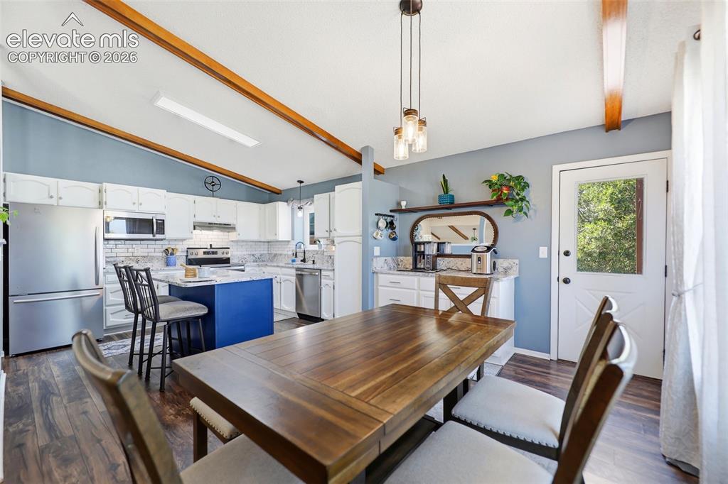 Image 14 of 37: Open-concept kitchen and dining area featuring a vaulted ceiling with expos