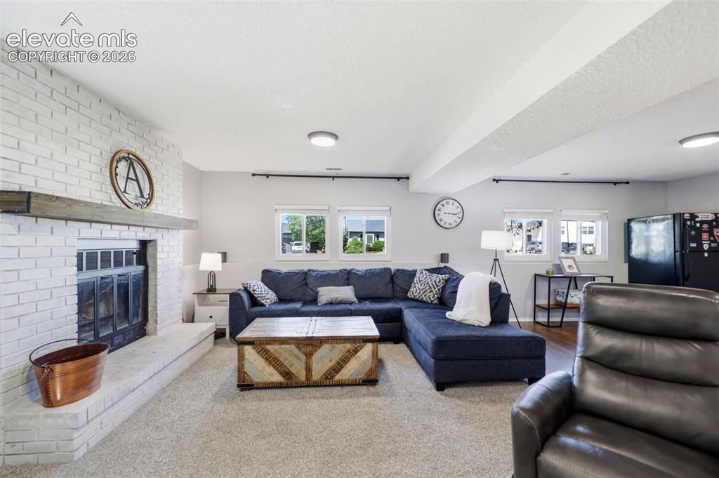 Image 22 of 37: Living area featuring a painted brick fireplace with a wood mantle, multipl