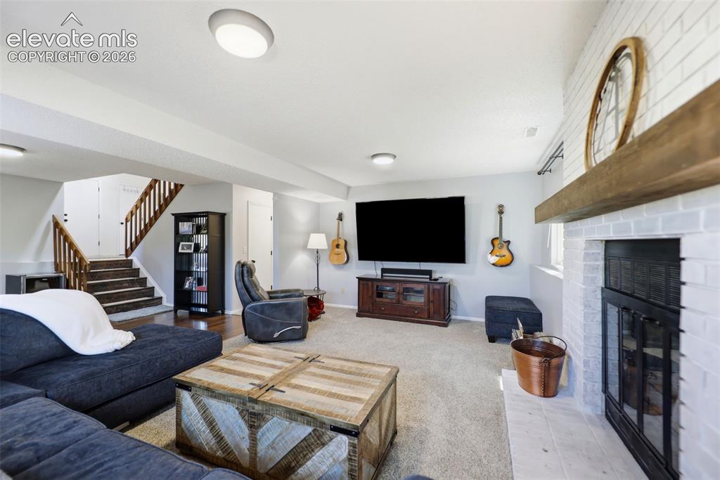 Image 23 of 37: Living area featuring a white brick fireplace with a wood mantle, recessed 