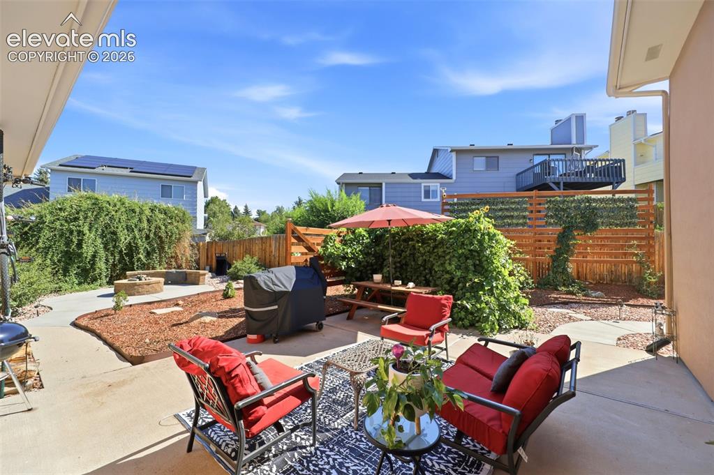 Image 28 of 37: Spacious backyard featuring a concrete patio, integrated fire pit with benc