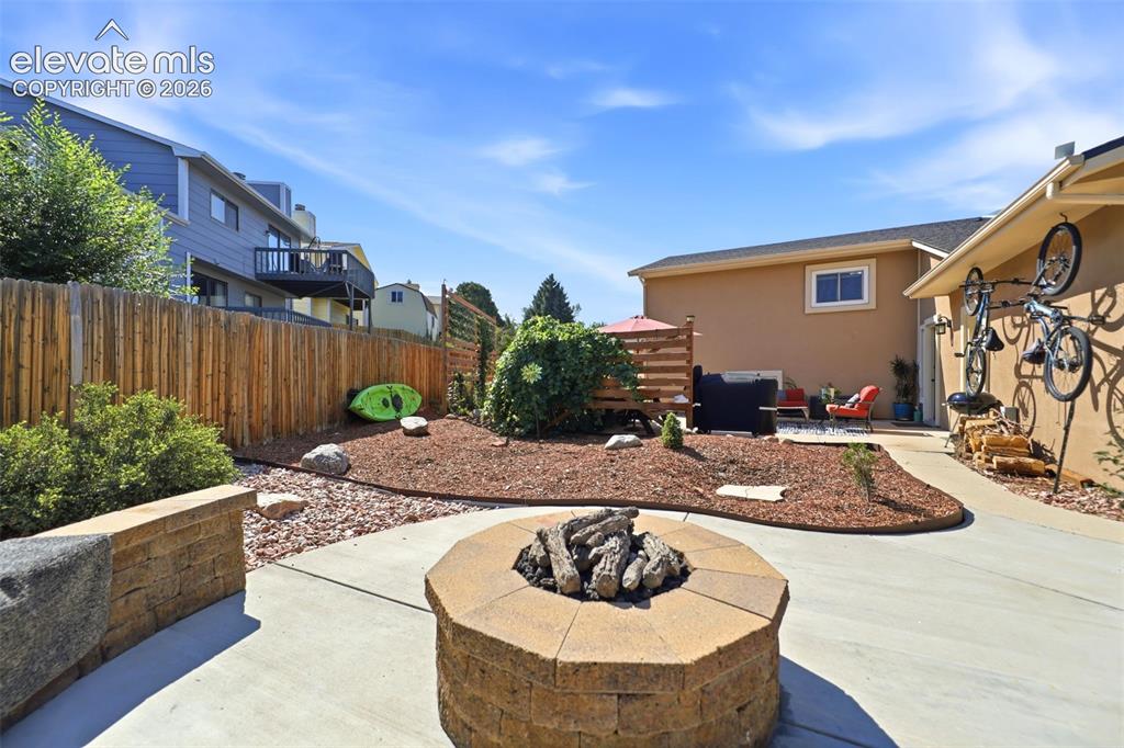 Image 37 of 37: Outdoor patio featuring a built-in fire pit, concrete paving, and a decorat