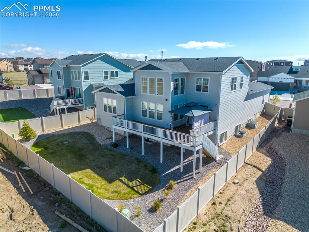 Image 3 of 9: Rear exterior featuring a two-story design with light gray siding, a dark s