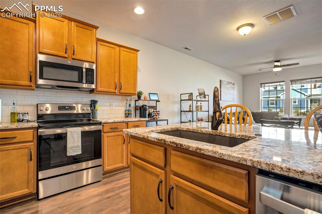 Image 14 of 48: Kitchen featuring stainless steel appliances, light stone countertops, wood