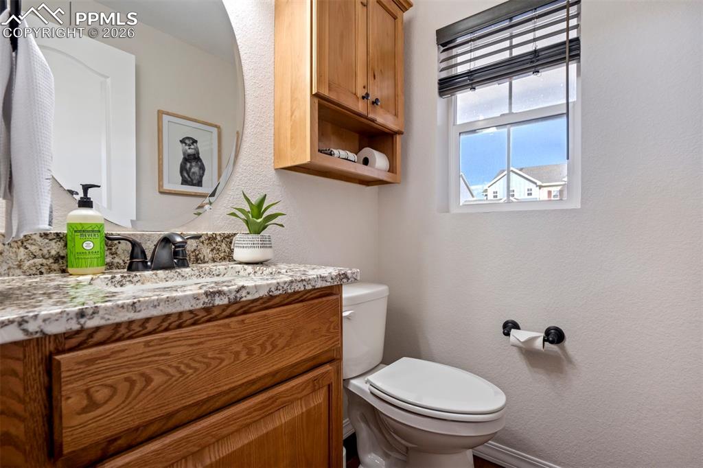 Image 18 of 48: Half bathroom with vanity with stone countertop.