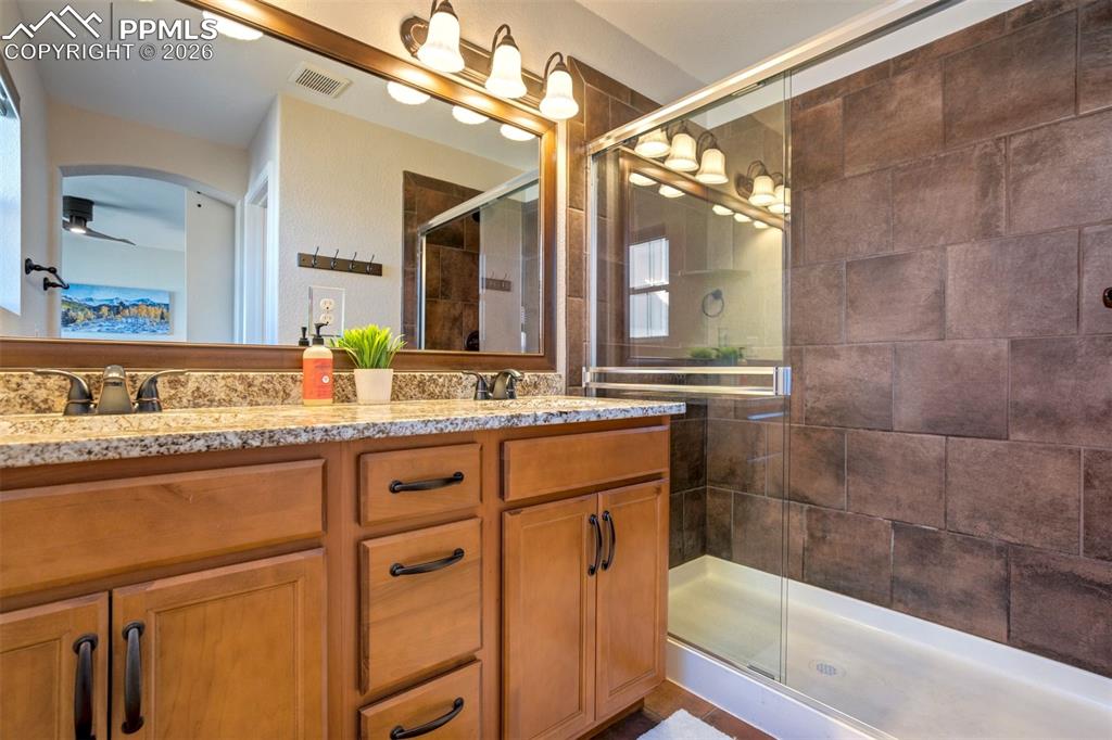 Image 27 of 48: Primary bathroom featuring double vanities, stone countertops and a large s
