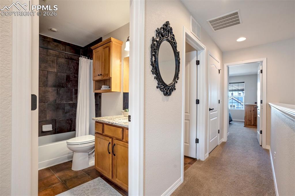 Image 34 of 48: Hallway bathroom showing the bath/shower and sink with stone countertop.  T