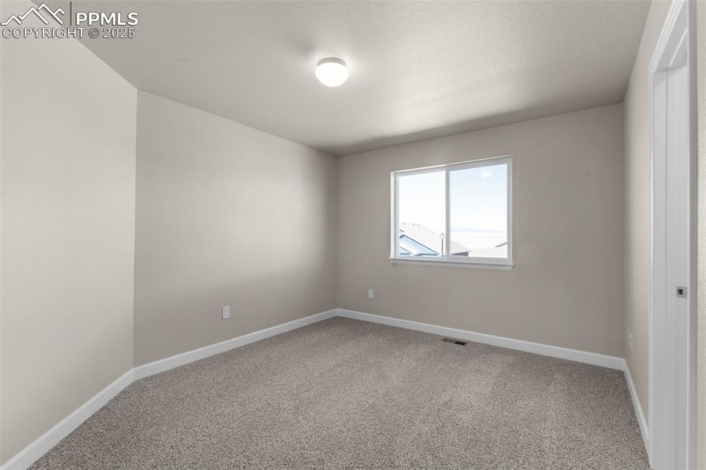 Image 12 of 13: Empty room featuring baseboards, carpet, and visible vents