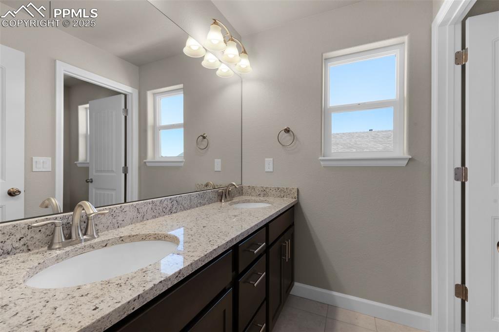 Image 13 of 13: Bathroom featuring a sink, baseboards, tile patterned flooring, and double 