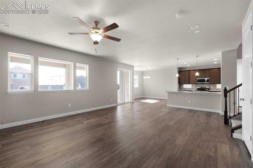 Image 4 of 13: Unfurnished living room featuring dark wood-style flooring, stairway, baseb
