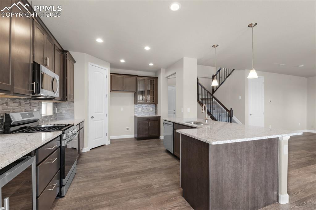 Image 6 of 13: Kitchen with wine cooler, dark brown cabinetry, dark wood-style floors, a s