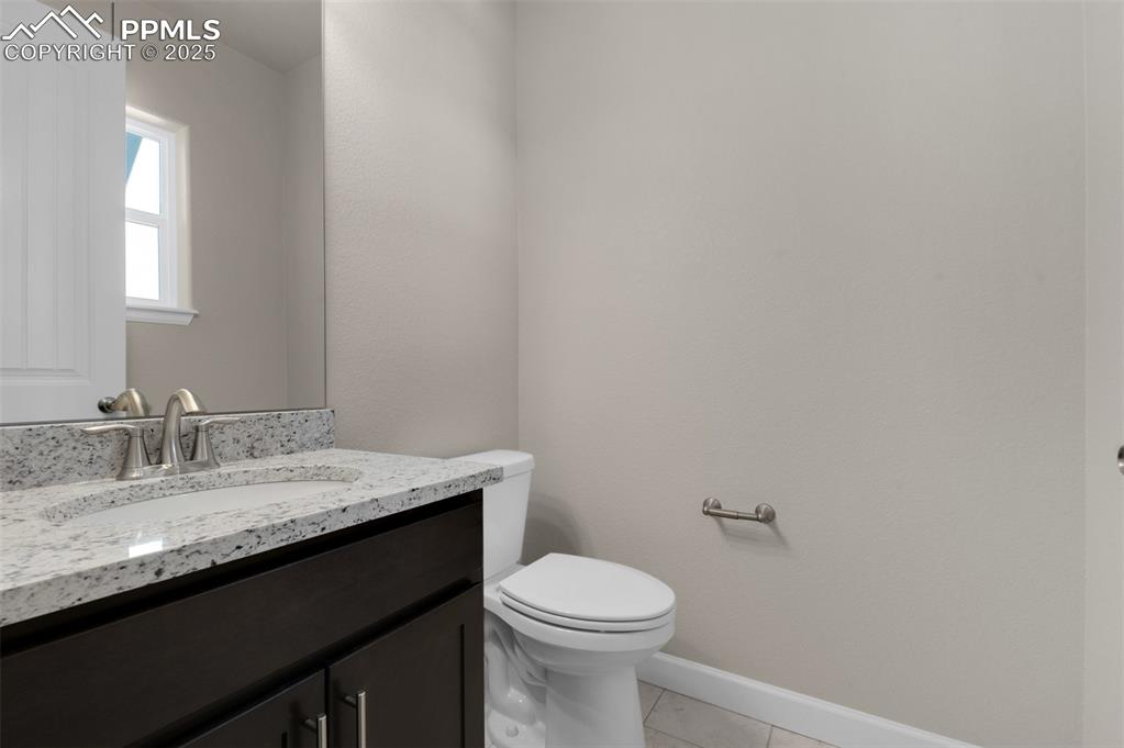 Image 7 of 13: Half bath featuring toilet, baseboards, tile patterned floors, and vanity
