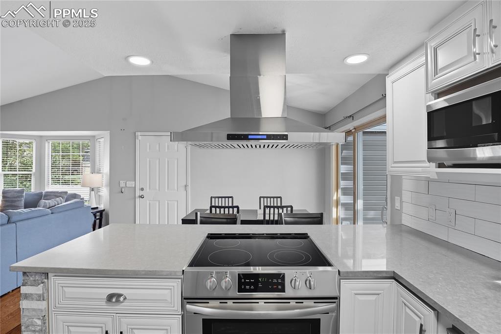 Image 12 of 32: Kitchen featuring white cabinetry, stainless steel appliances, a peninsula,