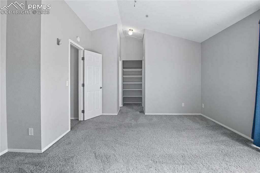 Image 19 of 32: Unfurnished bedroom featuring light colored carpet, lofted ceiling, and a c