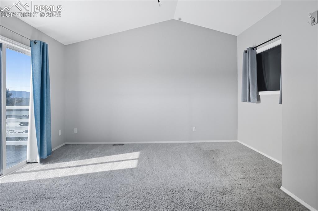 Image 20 of 32: Carpeted empty room featuring vaulted ceiling and baseboards