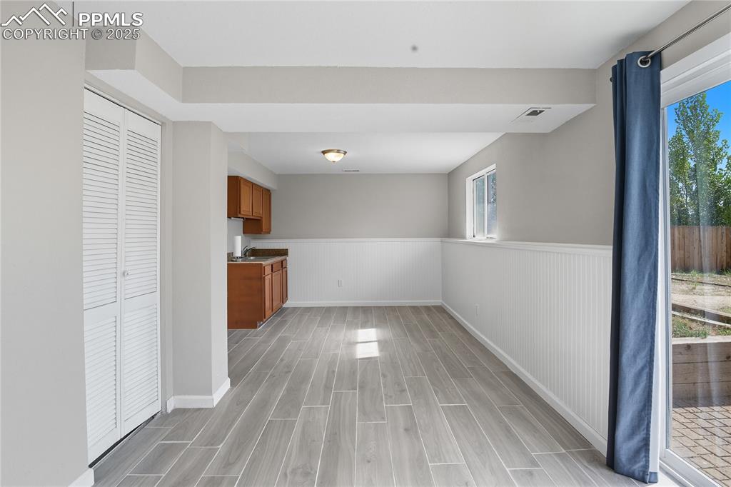 Image 24 of 32: Unfurnished dining area featuring wainscoting and wood finish floors