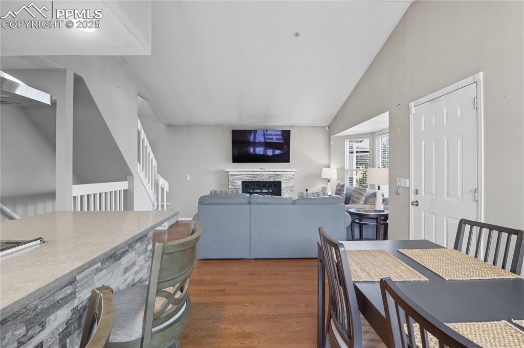 Image 7 of 32: Dining space with dark wood-style flooring, lofted ceiling, a stone firepla