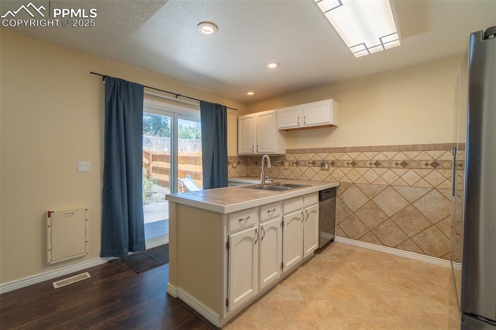 Image 10 of 42: Kitchen featuring tile walls, a peninsula, stainless steel appliances, rece