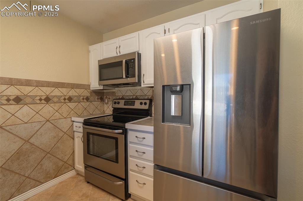 Image 11 of 42: Kitchen featuring stainless steel appliances, white cabinetry, light counte