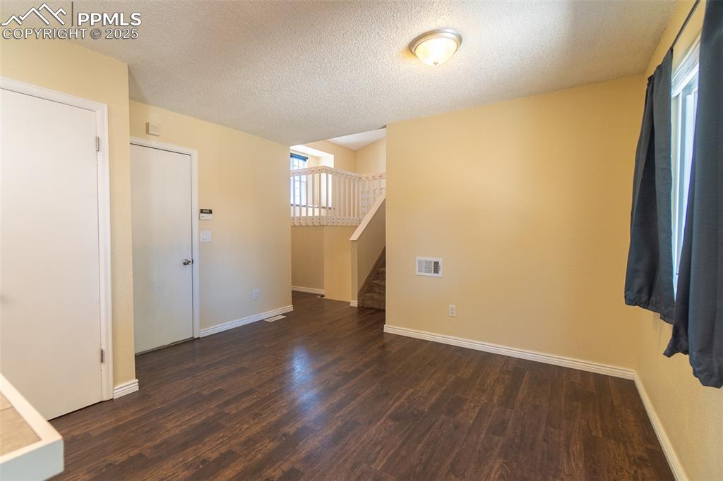 Image 15 of 42: Dining room with dark wood-type flooring, a textured ceiling, and stairway