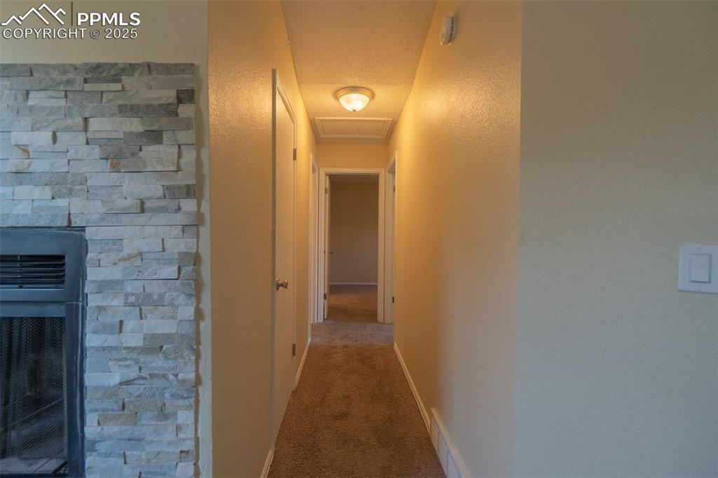 Image 16 of 42: Hall with carpet flooring, a textured wall, a textured ceiling, and attic a