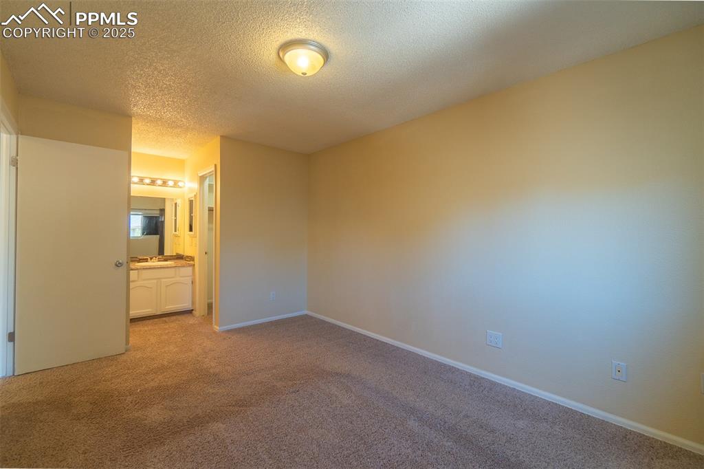 Image 18 of 42: Master bedroom with carpet floors, a textured ceiling, and ensuite bathroom