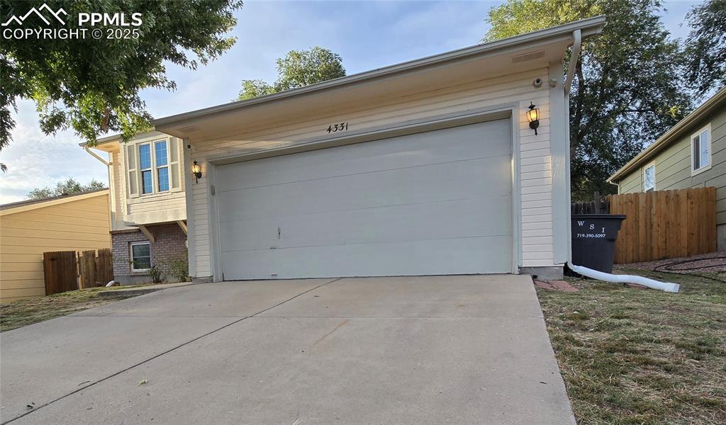 Image 2 of 42: View of front of property with a garage, brick siding, and concrete drivewa