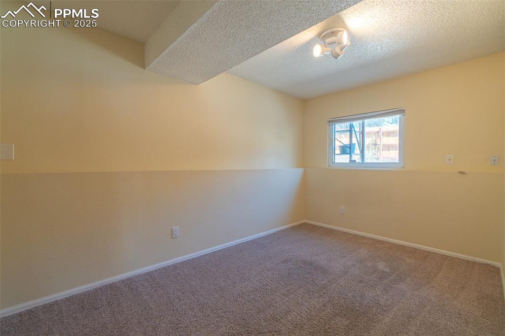 Image 22 of 42: Bedroom on upper level, carpeted empty room featuring a textured ceiling an