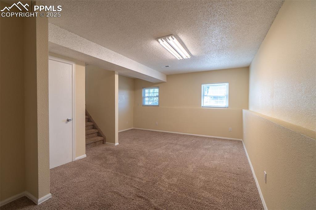 Image 23 of 42: Finished family room  featuring carpet flooring, stairway, a textured ceili