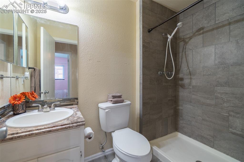 Image 32 of 42: Full bath featuring a textured wall, vanity, and a shower stall