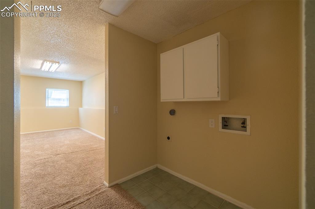 Image 33 of 42: Laundry room, located on the lower level, featuring a textured ceiling, hoo