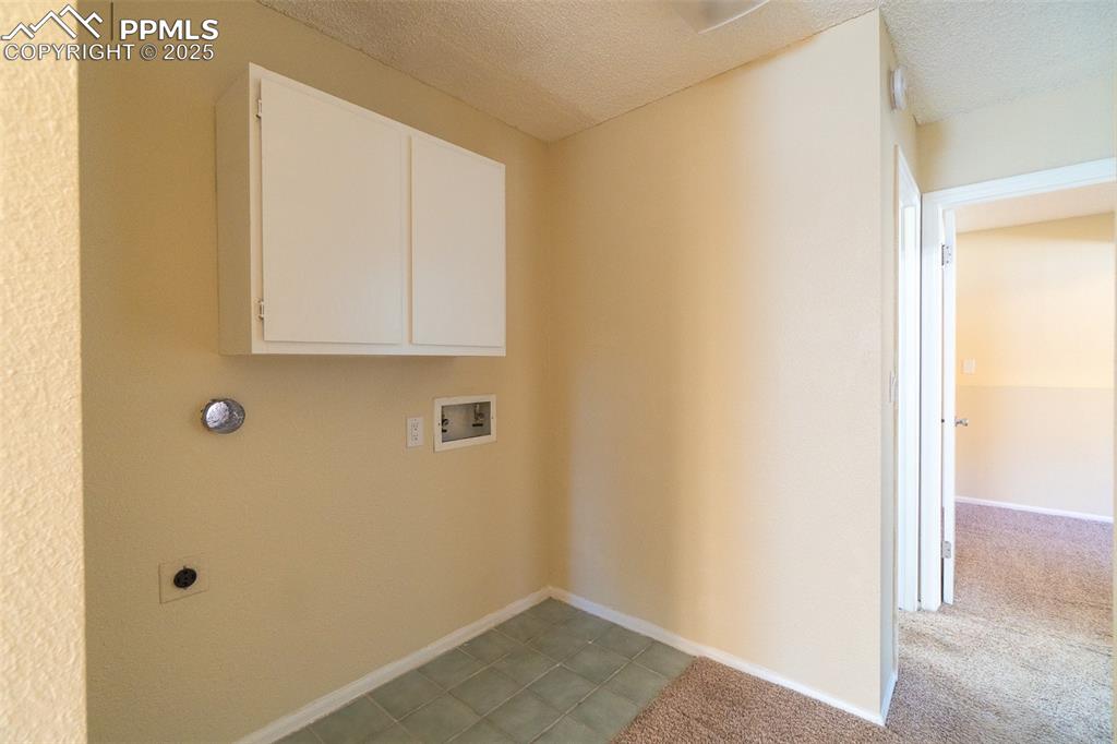 Image 34 of 42: Laundry room featuring washer hookup, a textured ceiling, cabinet space, el