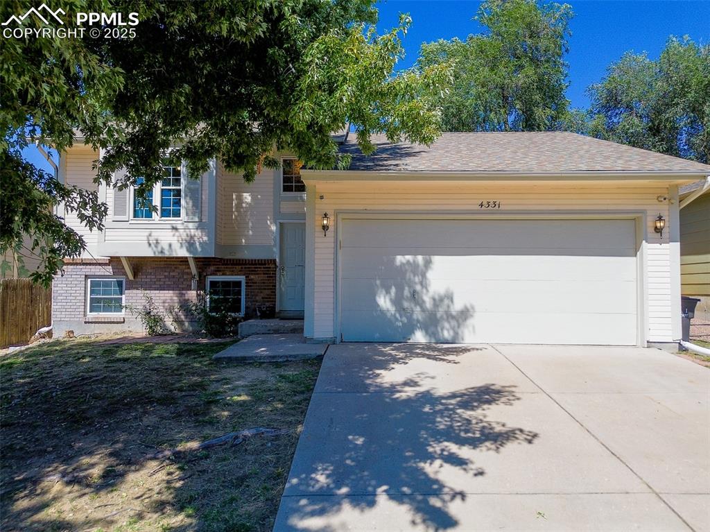 Image 42 of 42: Tri-level home with brick siding, driveway, and an attached garage