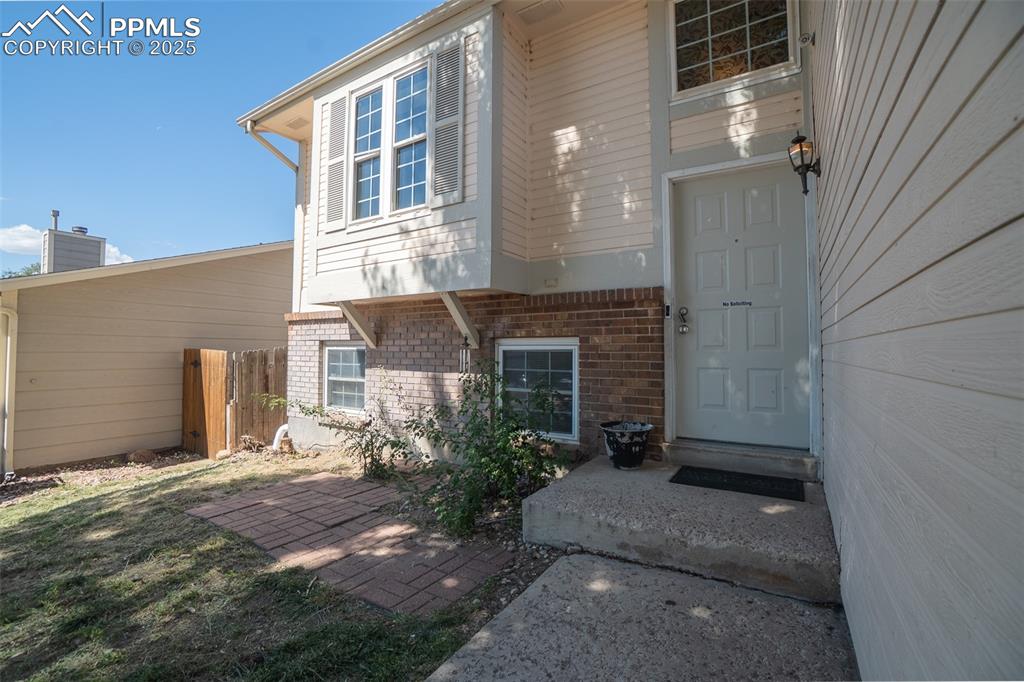 Image 5 of 42: View of exterior entry with brick siding and a chimney