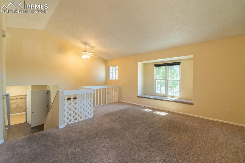 Image 7 of 42: Unfurnished room with carpet floors, vaulted ceiling, and a textured ceilin
