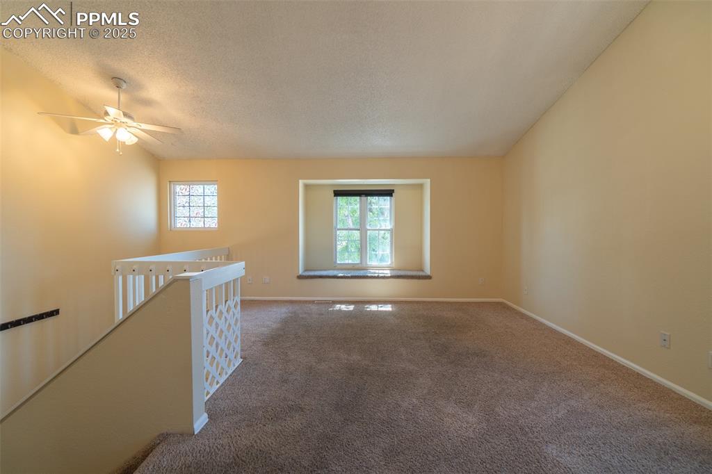 Image 8 of 42: Living room with carpet floors, a ceiling fan, lofted ceiling, and a textur