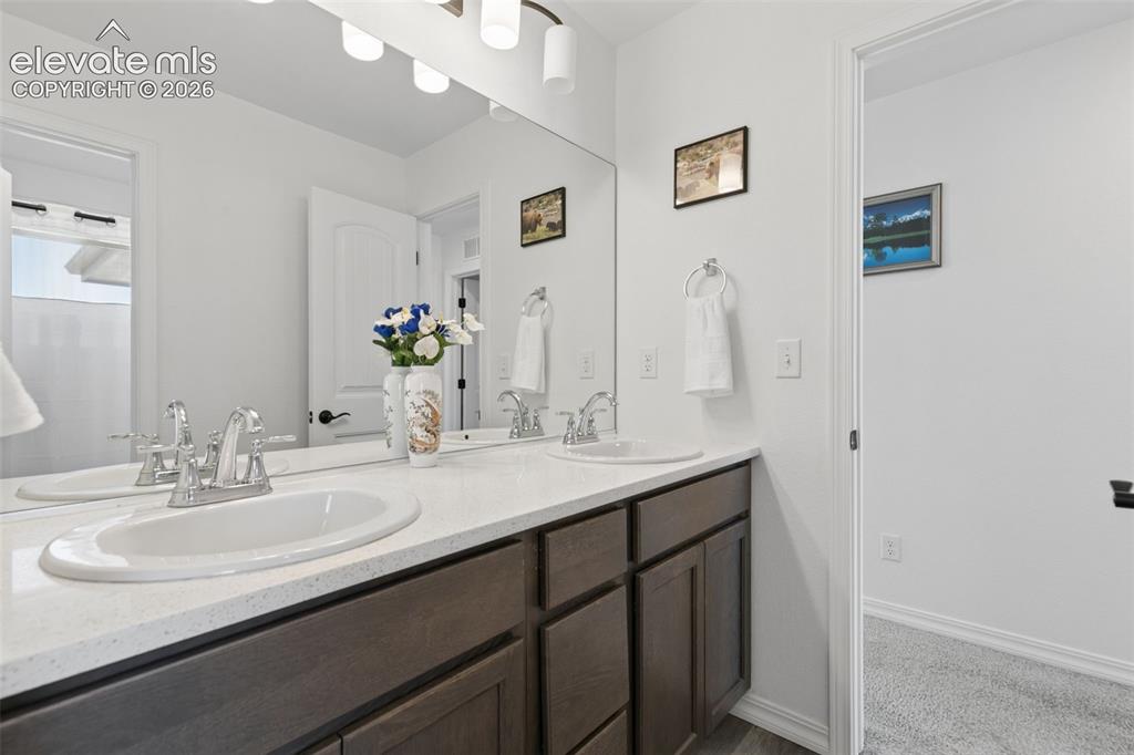 Image 18 of 26: Double vanity with white oval undermount sinks, chrome fixtures, and a ligh