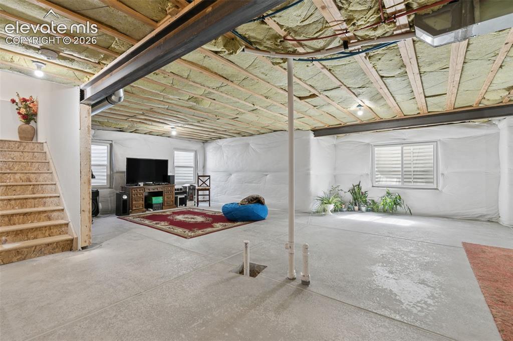 Image 20 of 26: Expansive lower level with concrete flooring, exposed ceiling joists, and e