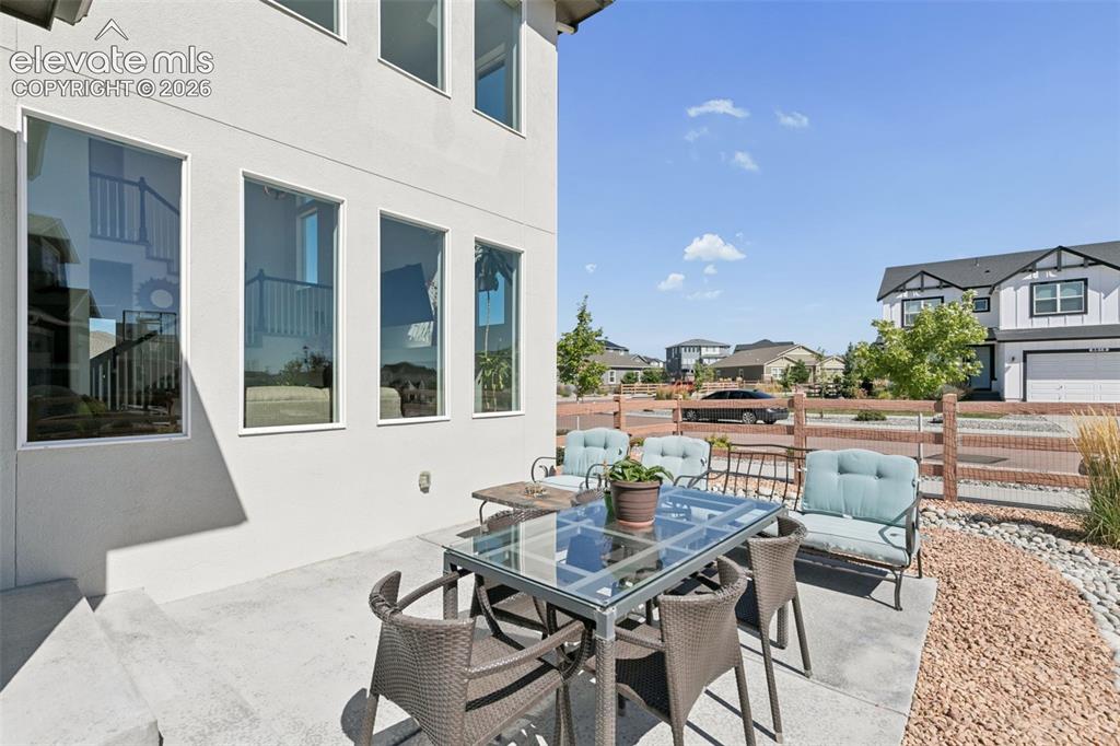 Image 23 of 26: Exterior stucco finish, multiple large windows, concrete patio, gravel land