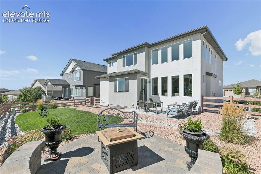 Image 25 of 26: Expansive backyard featuring a stone patio, manicured lawn, and surrounding
