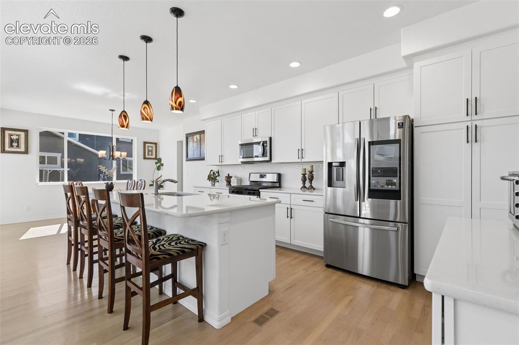 Image 6 of 26: Kitchen featuring white cabinetry, stainless steel appliances, light wood-f
