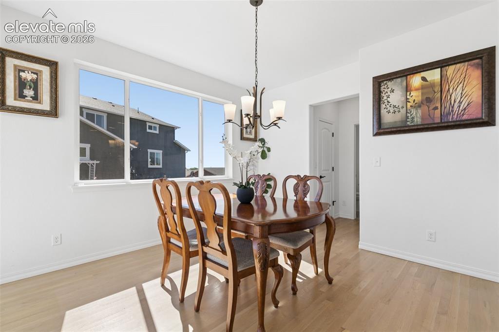 Image 8 of 26: wood-finish flooring, white walls, white trim, and a bronze-finish chandel