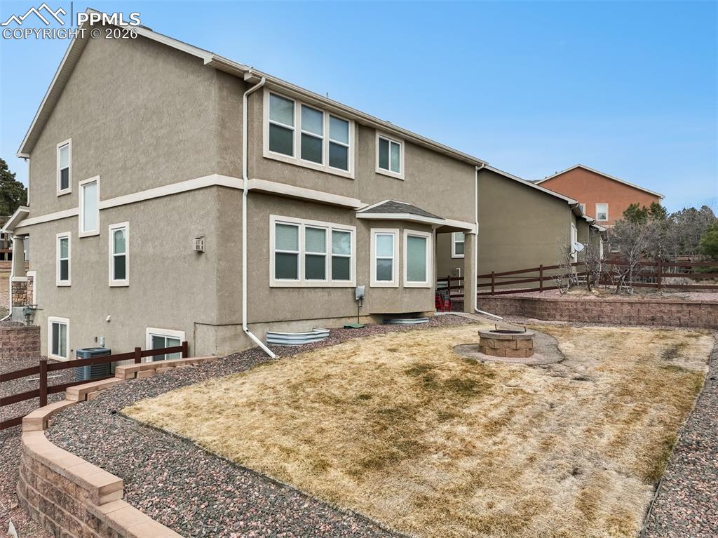 Image 47 of 50: Fenced back yard with landscaping, sprinklers, fire pit and patio access