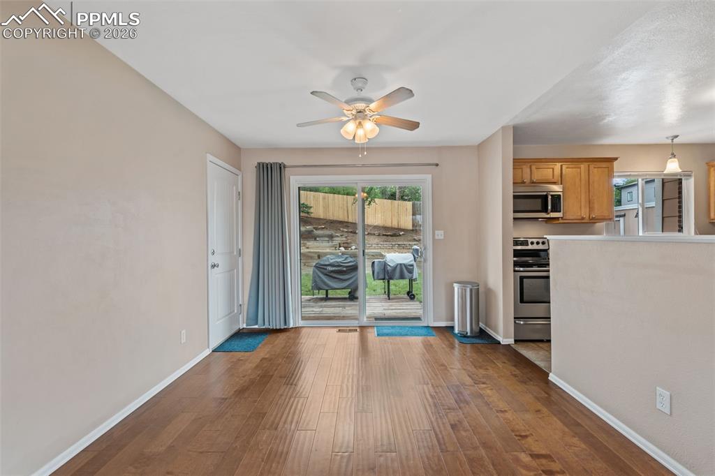 Image 11 of 40: Unfurnished dining area with dark wood-style flooring and ceiling fan